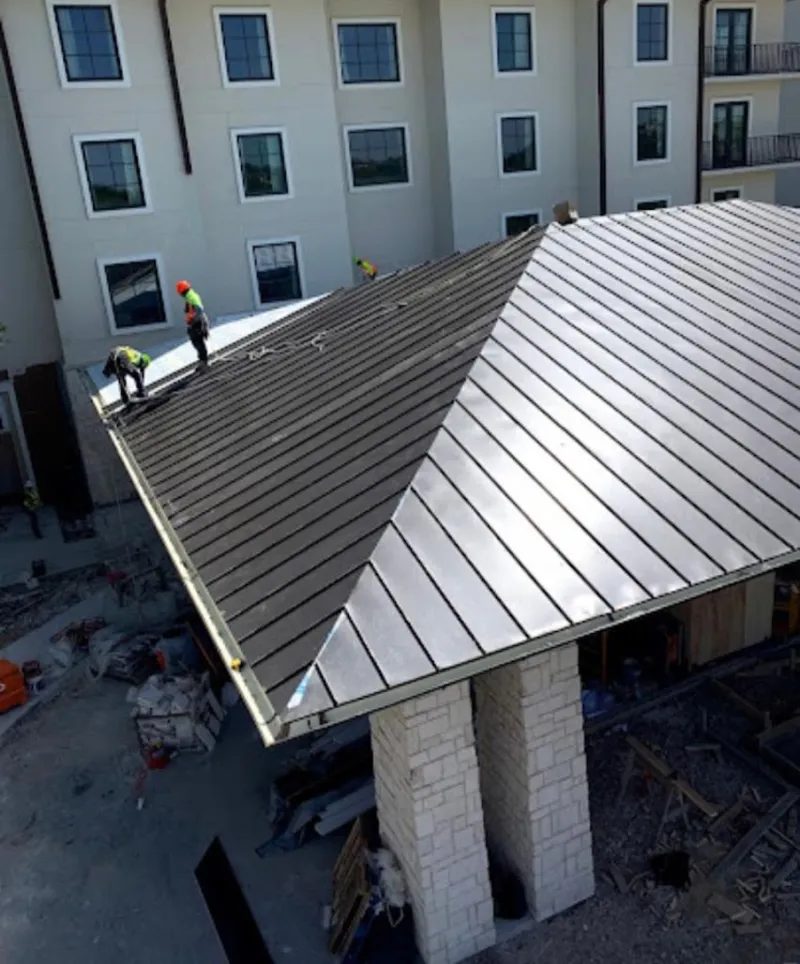Crew installing standing seam metal roof panels on a commercial project in Clinton